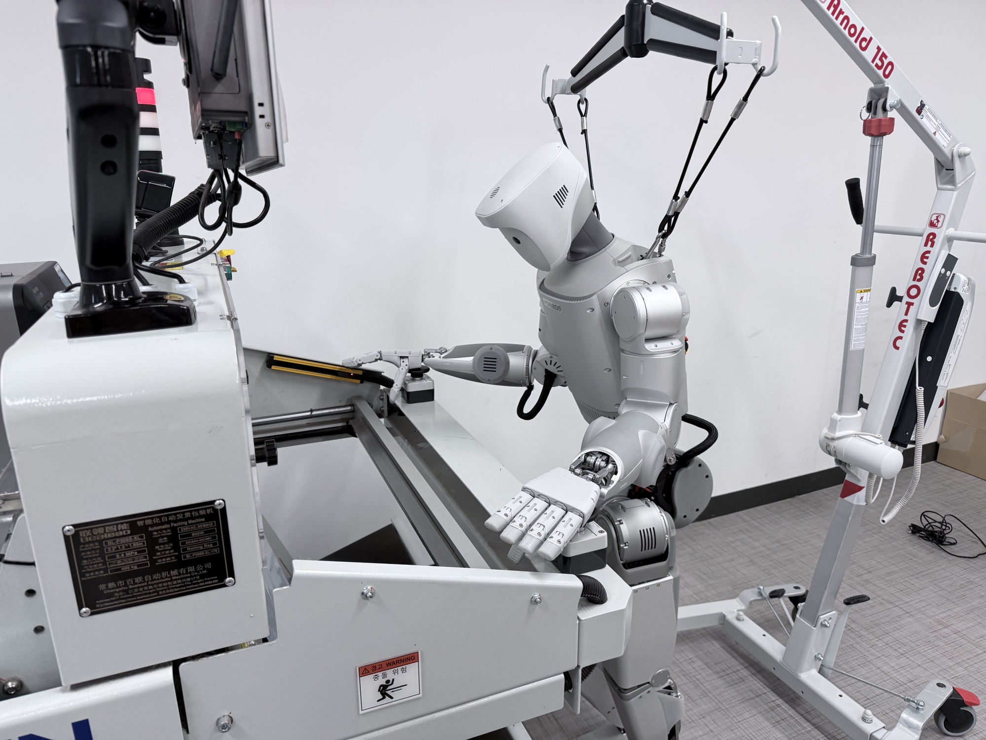 Humanoid robot operating an auto-bagger machine in the lab